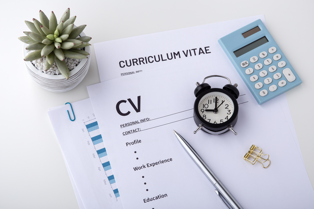 CV with pen and clock on white desk